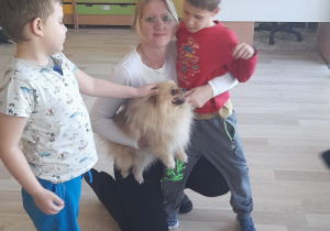 Zajęcia z dogoterapii - na zdjęciu Pani Aneta, Michał i Yaroslav głaszczą pieska.