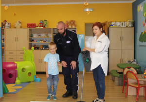 Adaś z funkcjonariuszem Policji podczas ćwiczeń przechodzenia przez jezdnię (ćwiczenia w sali)