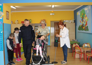 Marika z panią Elą i funkcjonariuszem Policji podczas ćwiczeń przechodzenia przez jezdnię (ćwiczenia w sali)