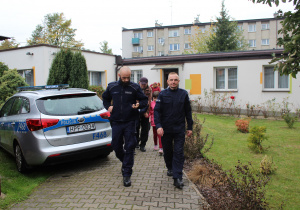 Funkcjonariusze Policji, w tle przedszkolaki z wychowawcami w drodze na przejście dla pieszych