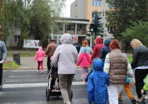 Przedszkolaki podczas przechodzenia przez ulicę pod opieką funkcjonariusza Policji i wychowawców