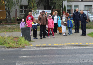 Przedszkolaki podczas przechodzenia przez ulicę pod opieką funkcjonariusza Policji i wychowawców