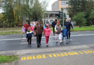 Przedszkolaki podczas przechodzenia przez ulicę pod opieką funkcjonariusza Policji i wychowawców