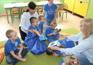 Zabawa "Czarodziejski worek" - na zdjęciu Krzysiu z paniami Kingą i Małgosią, wokół pozostałe dzieci