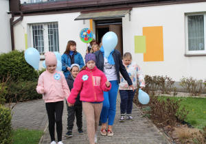 Niebieski przemarsz - dzieci pod opieką pań wychodzą z budynku przedszkola