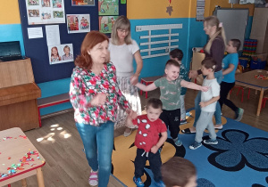 Dzieci z Paniami maszerują po kole w rytm muzyki.