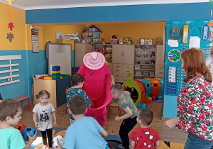 Dzieci wrzucają kolorowe piłki do szerokich spodni klauna.