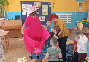 Dzieci wrzucają kolorowe piłki do szerokich spodni klauna..