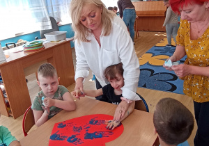 Dzieci z grupy 3 odbijają swoje dłonie na czerwonym sercu.