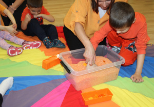 Dzień pomarańczowy -na zdjęciu Ksawery poszukuje skarbów w pomarańczowym ryżu