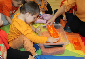 Dzień pomarańczowy - na zdjęciu Antoś poszukuje skarbów w pomarańczowym ryżu