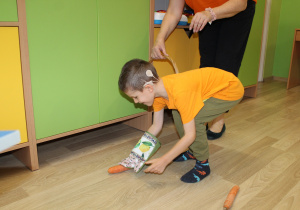 Dzień pomarańczowy - na zdjęciu Michał zbiera marchewki w kuchennej rękawicy