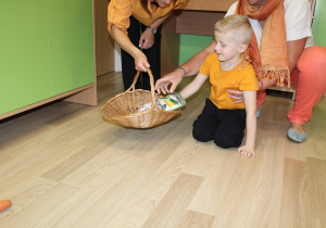 Dzień pomarańczowy - na zdjęciu Filip zbiera marchewki w rękawicy kuchennej