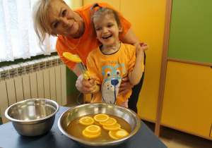 Dzień pomarańczowy - na zdjęciu Nadia z pomocą p. Małgosi łowi plastry pomarańczy