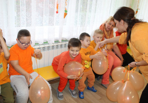 Dzień pomarańczowy - na zdjęciu p. Kinga rozdaje dzieciom pomarańczowe baloniki