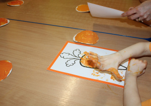 Dzień pomarańczowy - na zdjęciu dziecko w trakcie kolorowania marchewki paluszkami