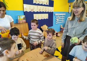 Chłopcy szukają misiów w wiaderkach z różnymi materiałami.