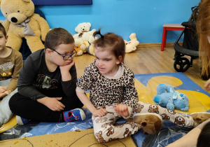Dzieci wyklejają misia różnymi materiałami.