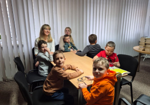 Chłopcy z p. Kasią i z p. Anetą siedzą wokół stołu w bibliotece.