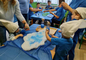 Dzień niebieski - dzieci z grupy II kolorują chmurki spryskiwaczem z niebieską farbą.