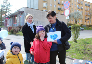 Przedszkolne obchody Dni Autyzmu - na zdjęciu przedszkolaki wręczają niebieskie serduszka przechodniom
