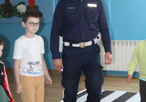 "Bezpieczna droga do przedszkola" - na zdjęciu Adaś z funkcjonariuszem Policji trakcie zabawy ruchowej