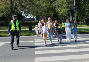 "Bezpieczna droga do przedszkola" - na zdjęciu przedszkolaki ćwiczą bezpieczne przechodzenie po pasach z sygnalizacją